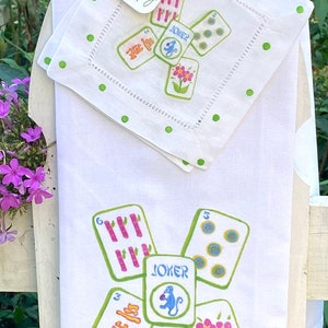 K&ouml;nnte beinhalten: Wei&szlig;es K&uuml;chentuch mit gr&uuml;nen Punkten und einem Design aus f&uuml;nf Spielkarten mit einem Affen auf der Jokerkarte. Die Karten sind in Form einer Blume angeordnet, wobei sich der Joker in der Mitte befindet. Das Tuch hat einen gr&uuml;nen Rand und der Text "Lemondaisy Design" befindet sich auf einem Etikett.