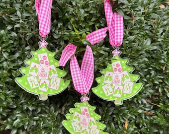May include: Three Christmas tree ornaments with a green base and a pink and white gingham ribbon. Each tree has a card game design with the number nine and other card symbols. The ornaments are hanging on a green bush.