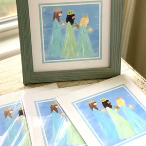 May include: Three figures in blue and green robes with gold crowns, holding gifts, on a blue background with a light blue border. The image is a print of a painting.