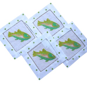 May include: Four white linen napkins with green polka dots and a green and pink fish design.
