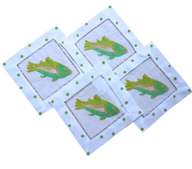 May include: Four white linen napkins with green polka dots and a green and pink fish design.