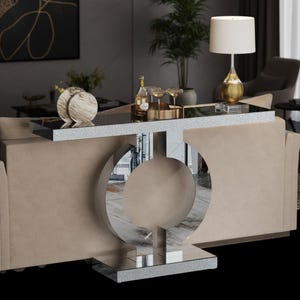 May include: A modern console table with a mirrored base and a black glass top. The table has a silver glitter trim and a unique circular design. The table is approximately 48 inches long and 16 inches wide.