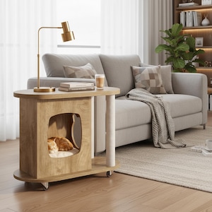 May include: A light oak wood side table featuring a built-in cat house with a cat-shaped entrance, a white cushioned interior, and a sisal-wrapped scratching post. The table is mounted on small wheels and has an oval top surface.