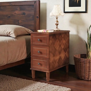 May include: A wooden nightstand with three drawers and a diamond pattern on the side. The nightstand is brown and has a small lamp on top. The drawers have round knobs. The nightstand is next to a bed with a brown headboard.