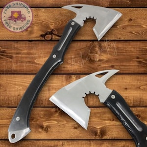 May include: Two axes with silver blades and black handles are displayed against a wooden background. The axes have a unique design with a curved blade and a toothed cutout near the head. The handles are black and appear to be made of a durable material.