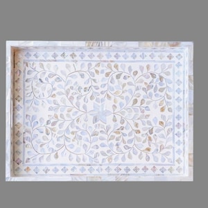 May include: Rectangular decorative tray with a white mother-of-pearl inlay. The tray features a floral design in shades of blue, gray, and brown. The border is decorated with small diamond shapes. A stylish accent piece for home decor.