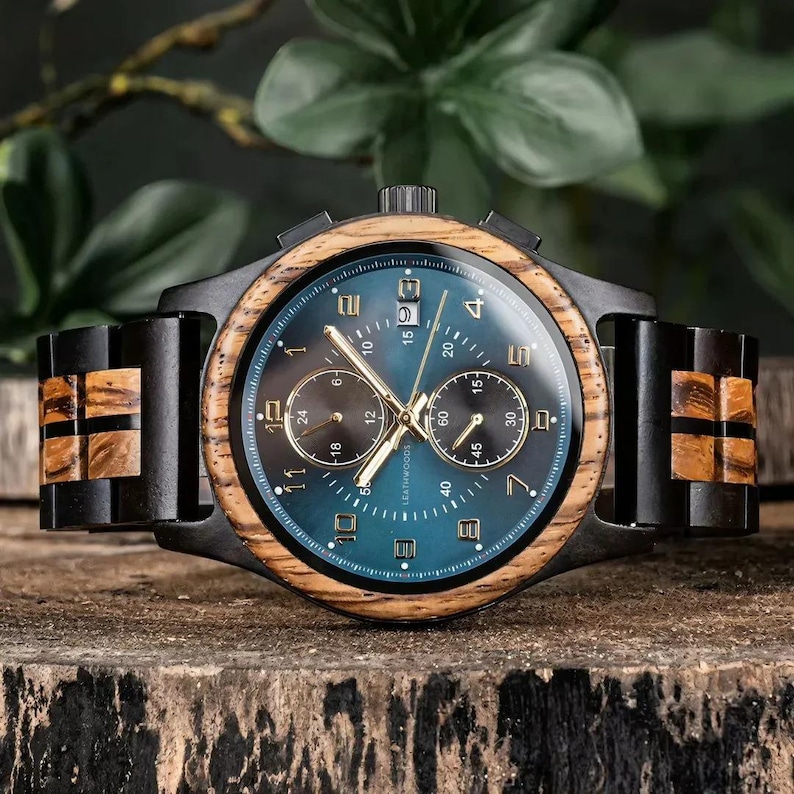 Side view of personalized Raven wooden watch laid on natural wood surface, showing ebony and zebrawood case and strap, handmade men’s watch gift