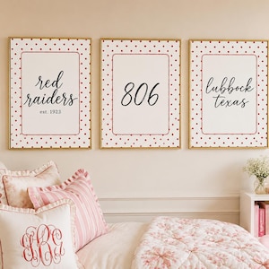 May include: Three rectangular wall art prints in gold frames featuring a white background with red polka dots. The prints display black text reading red raiders est. 1923, 806, and lubbock texas, each centered within a thin red rectangular border.