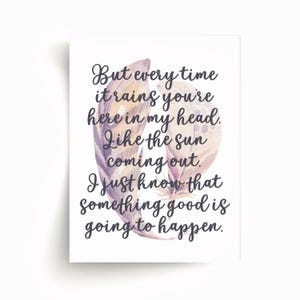 May include: White art print with the text "But every time it rains you're here in my head. Like the sun coming out. I just know that something good is going to happen." Features two watercolor feathers in shades of purple and tan.