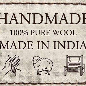 May include: A cream-colored fabric label with the words "HANDMADE", "100% PURE WOOL", and "MADE IN INDIA" in dark brown text. The label features illustrations of a hand with yarn, a sheep, and a loom.