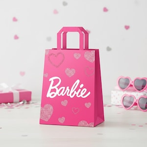 May include: A bright pink gift bag with the word "Barbie" in white script. The bag is decorated with glittery and solid pink hearts. Pink heart-shaped sunglasses and a wrapped gift are in the background.