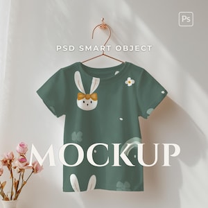 May include: Green t-shirt featuring a bunny face and bow tie design. The shirt has a round neck and short sleeves. The word "MOCKUP" is displayed in large, white letters across the bottom of the shirt.