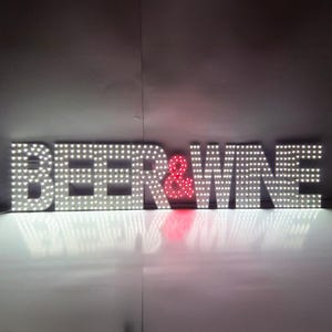 May include: Large illuminated sign spelling out "BEER & WINE". The letters are white and dotted with small lights. The ampersand is red and also lit. The sign is likely for a bar or restaurant.