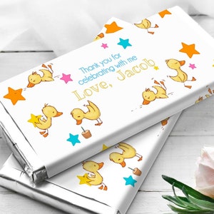 May include: A white chocolate bar with a colorful design featuring yellow ducks, stars, and the text "Thank you for celebrating with me Love, Jacob".