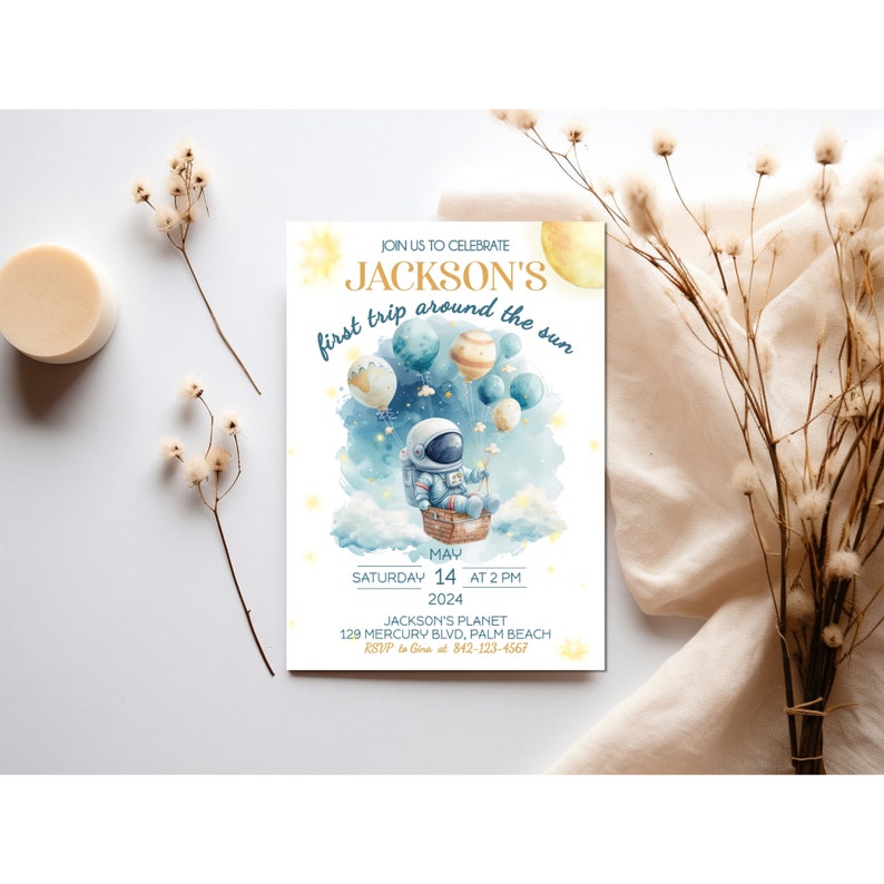 May include: A blue and yellow invitation card with a cartoon astronaut in a rocket ship. The text reads "Join us to celebrate Jackson's first trip around the sun. May 14 at 2 PM 2024. Jackson's Planet 129 Mercury Blvd, Palm Beach. RSVP to Gina at 842-123-4567."