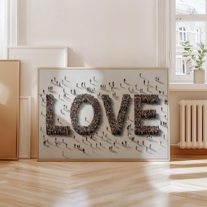 May include: A framed artwork featuring the word "LOVE" spelled out with a multitude of tiny figures. The figures are in various colors, creating a textured effect. The artwork is displayed on a light-colored wall.