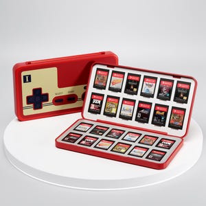 Peut inclure: Un étui rouge pour cartouches de jeux Nintendo Switch avec un design de manette rétro. L'étui est ouvert, révélant plusieurs cartouches de jeu. L'étui est rouge avec un panneau beige et une croix directionnelle bleue. L'étui est sur une surface blanche.