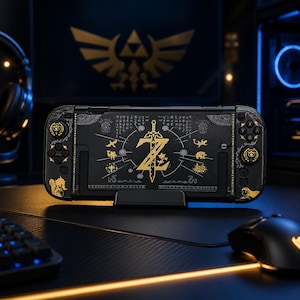 May include: A black handheld gaming console featuring gold-colored graphic designs, including a central sword emblem, various symbols, and intricate patterns. The device is mounted on a black stand, showcasing a detailed aesthetic inspired by fantasy themes.