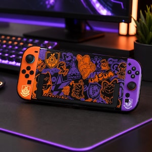 Könnte beinhalten: Eine tragbare Spielkonsole mit einer individuellen Schutzfolie in Schwarz, Orange und Violett, die verschiedene stilisierte Figuren und Embleme zeigt. Der linke Controller ist orange, der rechte violett und ein schwarzer Ständer ist angebracht.