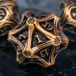 May include: A detailed image of a bronze-coloured, multi-sided die with elaborate carvings and visible numbers. The die features a geometric design with a metallic finish. The numbers are etched in a dark colour, providing contrast. Suitable for tabletop games.