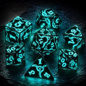 May include: A set of seven polyhedral dice featuring a black base with glowing cyan, intricate tentacle and eye patterns. The numbers are displayed in a matching glowing cyan font across the various geometric shapes, including a d20, d12, d10, d8, d6, and d4.