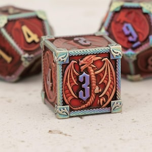 Peut inclure: Ensemble de dés rouges et bronze avec un motif de dragon. Les dés ont une finition métallique et présentent des chiffres dorés et bleus. Le dé au centre affiche le chiffre 3 et une illustration de dragon.