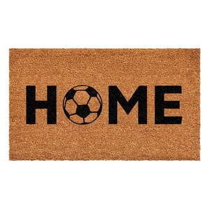 以下が含まれることがあります： 太い黒文字で「HOME」と書かれた長方形のベージュ色のココヤシ繊維製ドアマット。文字の「O」は、白黒のサッカーボールのグラフィックに置き換えられています。マットは天然素材特有の粗い繊維状の質感をしています。