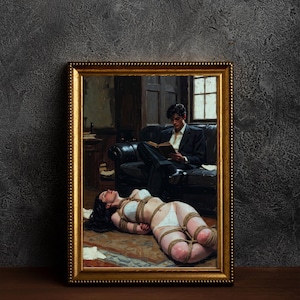 May include: Framed artwork showing a person bound with rope on the floor, with another person reading a book on a sofa. The artwork is in a gold frame and set against a dark textured wall.