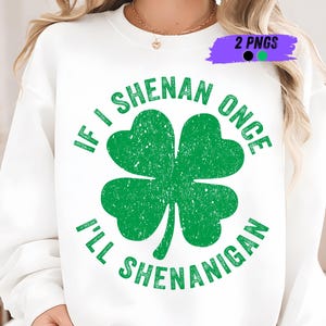 以下が含まれることがあります： 大きな緑のクローバーと「IF I SHENAN ONCE I'LL SHENANIGAN」のテキストがプリントされた白いスウェットシャツ。前面中央にデザインされ、聖パトリックの日に最適です。