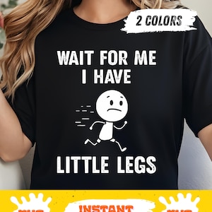 Könnte beinhalten: Schwarzes T-Shirt mit dem weißen Text "WAIT FOR ME I HAVE LITTLE LEGS". Eine weiße Strichmännchenfigur mit traurigem Gesicht rennt. Das Shirt hat auch ein "2 COLORS"-Etikett.