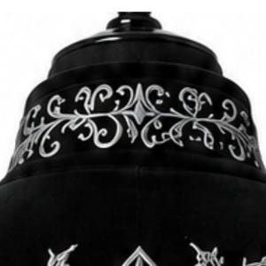 May include: A close-up of a black garment with silver embroidery. The design includes scrolling floral patterns and a fleur-de-lis motif, giving a gothic or regal appearance. The garment seems to be made of a soft, dark fabric.