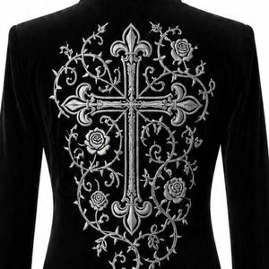 May include: Black velvet jacket with silver embroidery. The back has a large cross design with floral and vine details. The collar and cuffs also have silver embroidered accents. A gothic-inspired garment.