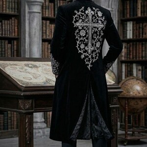 May include: A long black velvet coat with silver embroidery. The coat has a large cross design on the back, with floral patterns. The coat reaches the ankles and has a split back. The sleeves and collar are also embellished with silver embroidery. A gothic style garment.