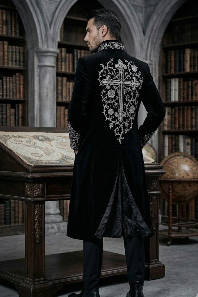 May include: A long black velvet coat with silver embroidery. The coat has a large cross design on the back, with floral patterns. The coat reaches the ankles and has a split back. The sleeves and collar are also embellished with silver embroidery. A gothic style garment.