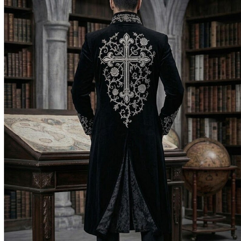 May include: Black velvet coat with silver embroidery, featuring a cross design on the back. The coat has a high collar and decorative cuffs. The long coat has a split back.