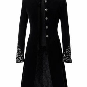 May include: A long, black velvet coat with a high collar and silver embroidered detailing. The coat features silver buttons down the front and ornate embroidery on the cuffs. The coat is displayed on a mannequin.