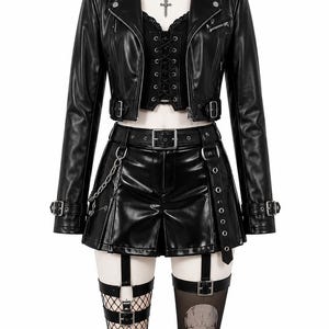 Könnte beinhalten: Eine schwarze Kunstleder-Motorradjacke, ein geschnürtes Korsett-Oberteil und ein plissierter Minirock mit Gürtel und Kette. Das Outfit umfasst ein Halsband mit Kreuzanhänger, Netzstrümpfe und einen Overknee-Strumpf mit Totenkopf-Motiv.