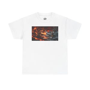 Puede incluir: Camiseta blanca con un gráfico rectangular que representa una escena de batalla ardiente con figuras y un cielo dramático. La obra de arte muestra un choque de guerreros en medio de llamas y humo.