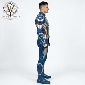 May include: A blue, silver, and dark red leather costume featuring a high collar, shoulder armor with a white star emblem, segmented chest plating, a utility belt, and matching trousers with reinforced knee panels, viewed from the side profile.