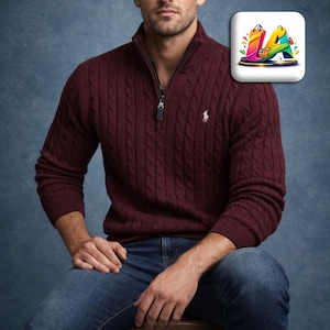 May include: A burgundy cable-knit sweater with a quarter-zip collar and a small white logo on the chest. The sweater is paired with blue jeans. The image has a shopping bag icon in the upper right corner.