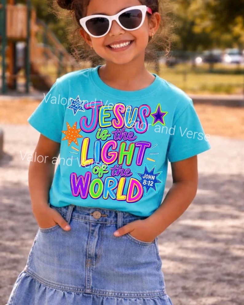May include: A bright turquoise short-sleeve t-shirt featuring the colorful text "JESUS is the LIGHT of the WORLD" and "JOHN 8:12" in a bold, multi-colored font. The design is accented with various star shapes in orange, blue, and purple colors.