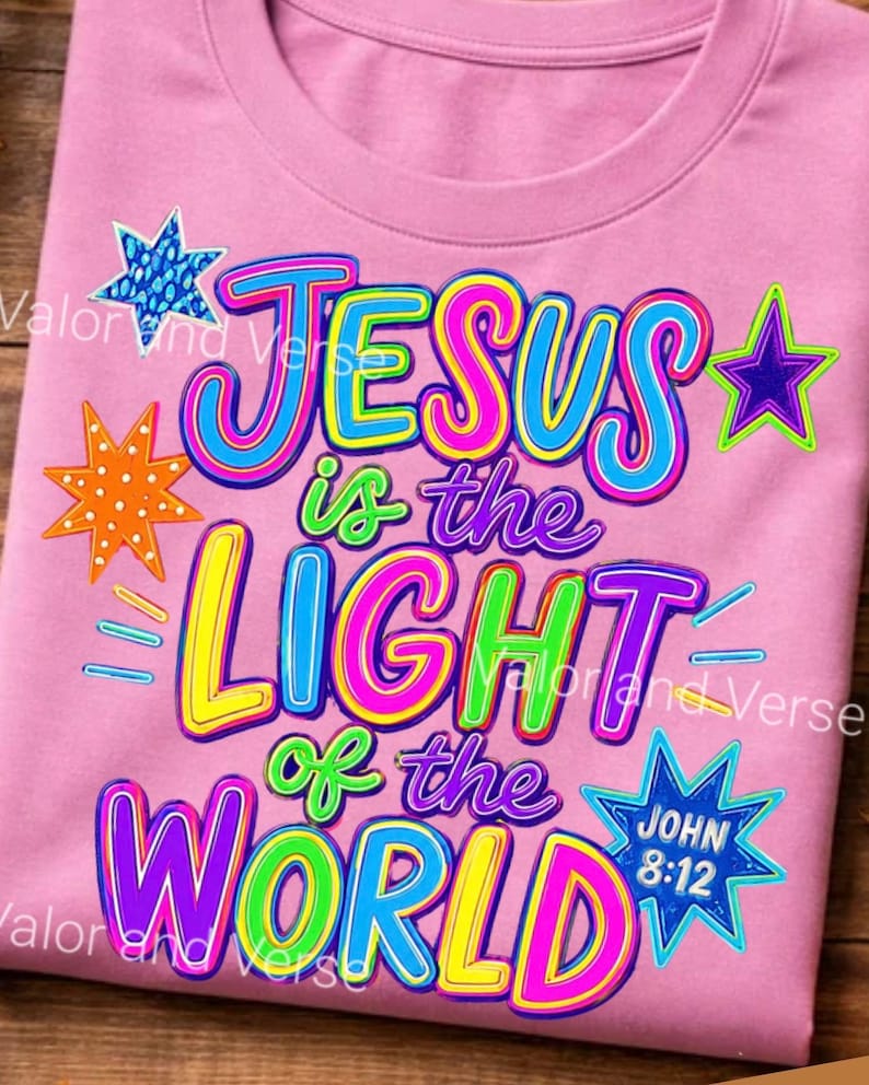 May include: A light pink t-shirt featuring a colorful graphic with the text "JESUS is the LIGHT of the WORLD" and "JOHN 8:12". The design includes various multi-colored stars in blue, orange, and purple, with bright lettering in yellow, pink, blue, and green.