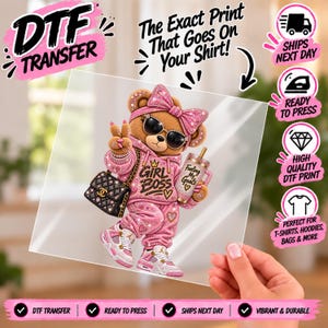 Puede incluir: Una hoja de transferencia DTF con un oso de peluche marrón que lleva una sudadera rosa con el texto GIRL BOSS, pantalones de chándal rosas, un lazo grande, gafas de sol y zapatillas. El oso sostiene un vaso con el texto Fueling My Goals.