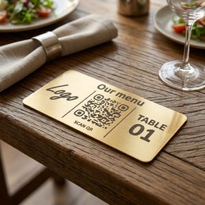 May include: A rectangular brass table sign with the text "Logo", "Our menu", "SCAN QR", and "TABLE 01". The sign is on a wooden table next to a napkin and a wine glass.