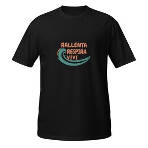 Può includere: T-shirt nero con la frase italiana "Rallenta Respira Vivi" in arancione e verde acqua, accompagnata da un'onda verde acqua. La maglietta è a girocollo.
