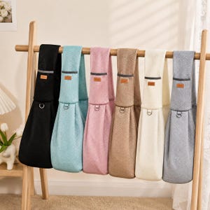 Puede incluir: Seis portamascotas de malla colgados en un soporte de madera, disponibles en negro, azul claro, rosa, beige, crema y gris. Cada transport&iacute;n cuenta con una correa ancha para el hombro, una etiqueta marr&oacute;n rectangular, una banda reflectante y una anilla en D.