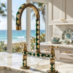 Può includere: Un rubinetto da cucina a ponte con bocca ad arco alto e due manopole. L'accessorio è realizzato in ottone con inserti decorativi a motivi circolari color verde e crema lungo la bocca, la base e i componenti delle manopole.