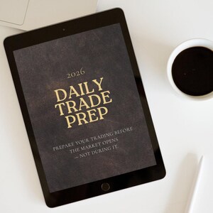 Peut inclure: Une tablette noire affichant "2026 DAILY TRADE PREP" en lettres dorées, avec le texte "PREPARE YOUR TRADING BEFORE THE MARKET OPENS - NOT DURING IT." Une tasse de café, un stylo et un ordinateur portable sont également visibles.