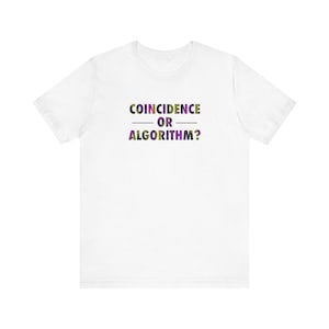 Op de afbeelding: Wit t-shirt met de tekst "COINCIDENCE — OR — ALGORITHM?" in groen, paars en zwart. De tekst staat in het midden op de voorkant. Het t-shirt is gemaakt van een zacht materiaal.