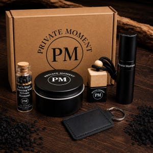 May include: A gift set in a brown cardboard box labeled Private Moment PM. Includes a small glass bottle of 15 safety matches, a black metal tin, a square glass diffuser with a wooden cap and black cord, a black spray bottle, and a black leather keychain.